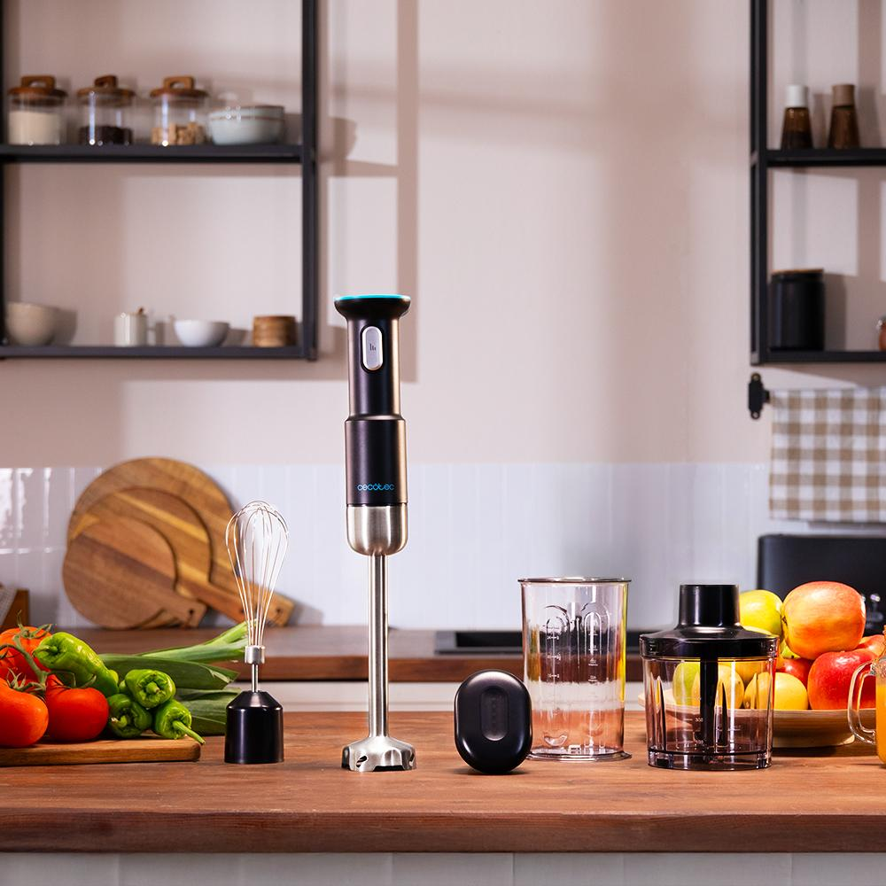 Una escena de cocina con una batidora, verduras y frutas en una encimera de madera. Estantes con frascos y utensilios de cocina al fondo.