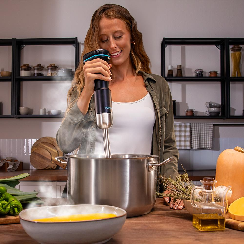 Mujer en la cocina mezclando sopa en una olla. Los ingredientes incluyen puerros, calabaza y aceite. Estantes y utensilios de cocina en el fondo.