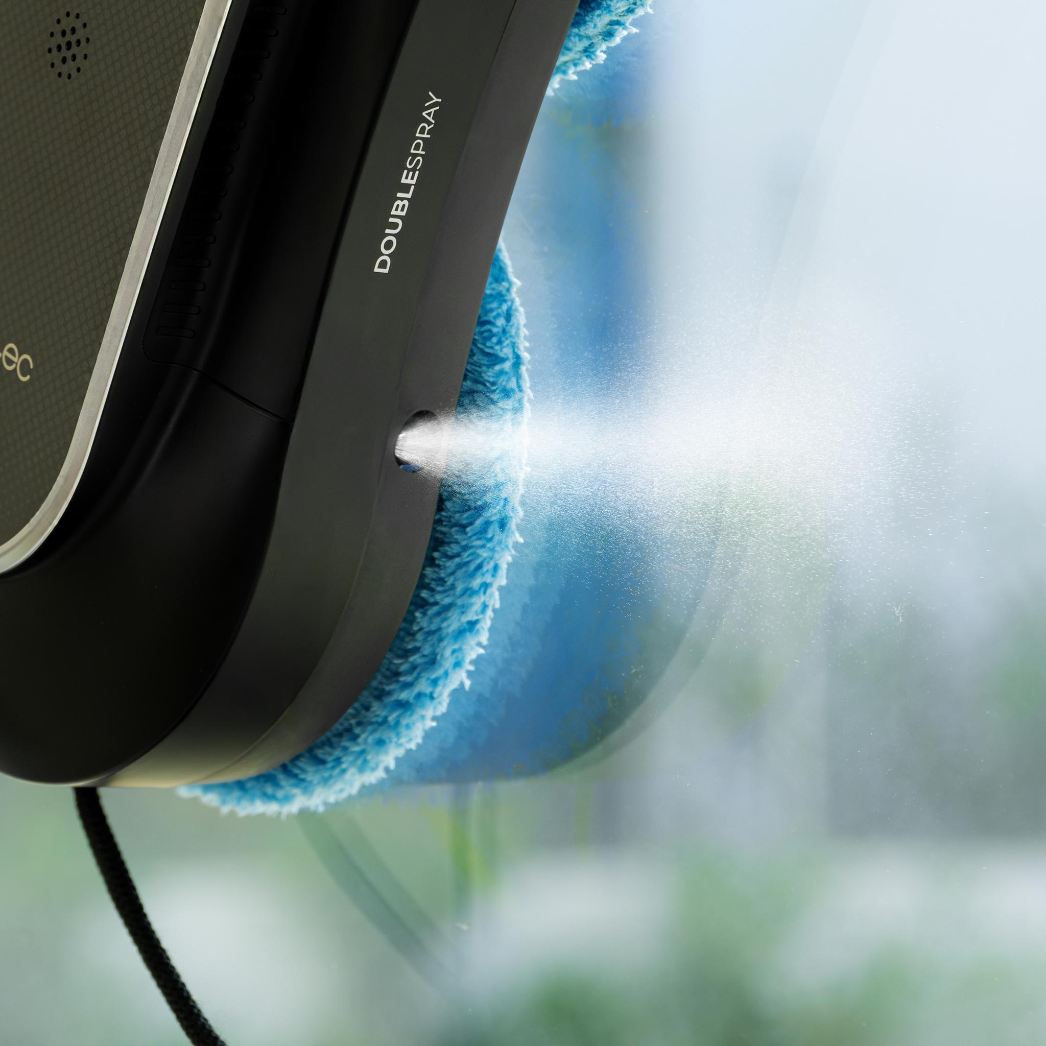 Un limpiador de ventanas negro y azul rocía agua sobre una ventana. Las palabras 'DOBLE SPRAY' son visibles.