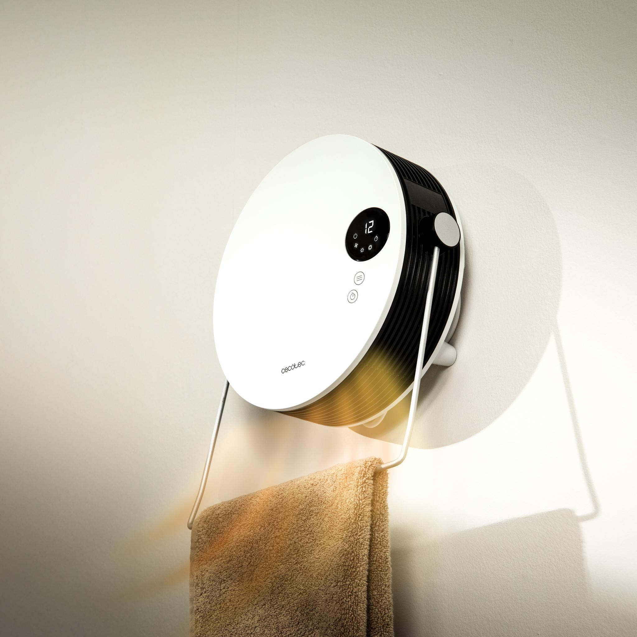 Un calefactor circular blanco y negro montado en la pared. Una toalla cuelga del soporte metálico del calefactor.