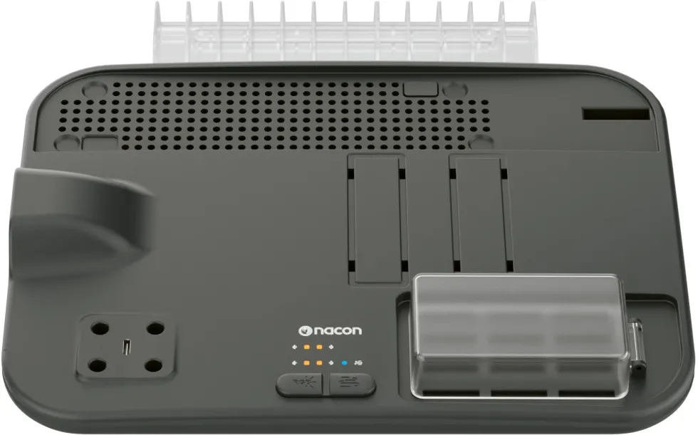Un dispositivo electrónico gris oscuro con una parte superior blanca. Tiene ventilaciones, botones, una cubierta de plástico transparente y el logotipo de Nacon.
