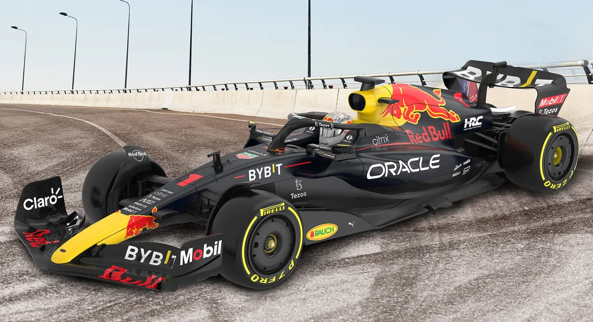 Egy fekete-piros Red Bull Formula 1-es autó a pályán. Az autón szponzorlogók vannak. Az ég szürke.