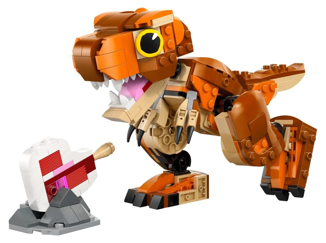Model Lego T-Rex, brązowy i pomarańczowy, otwiera pysk. Białe i różowe ciasto ze świecą leży na szarej skale.