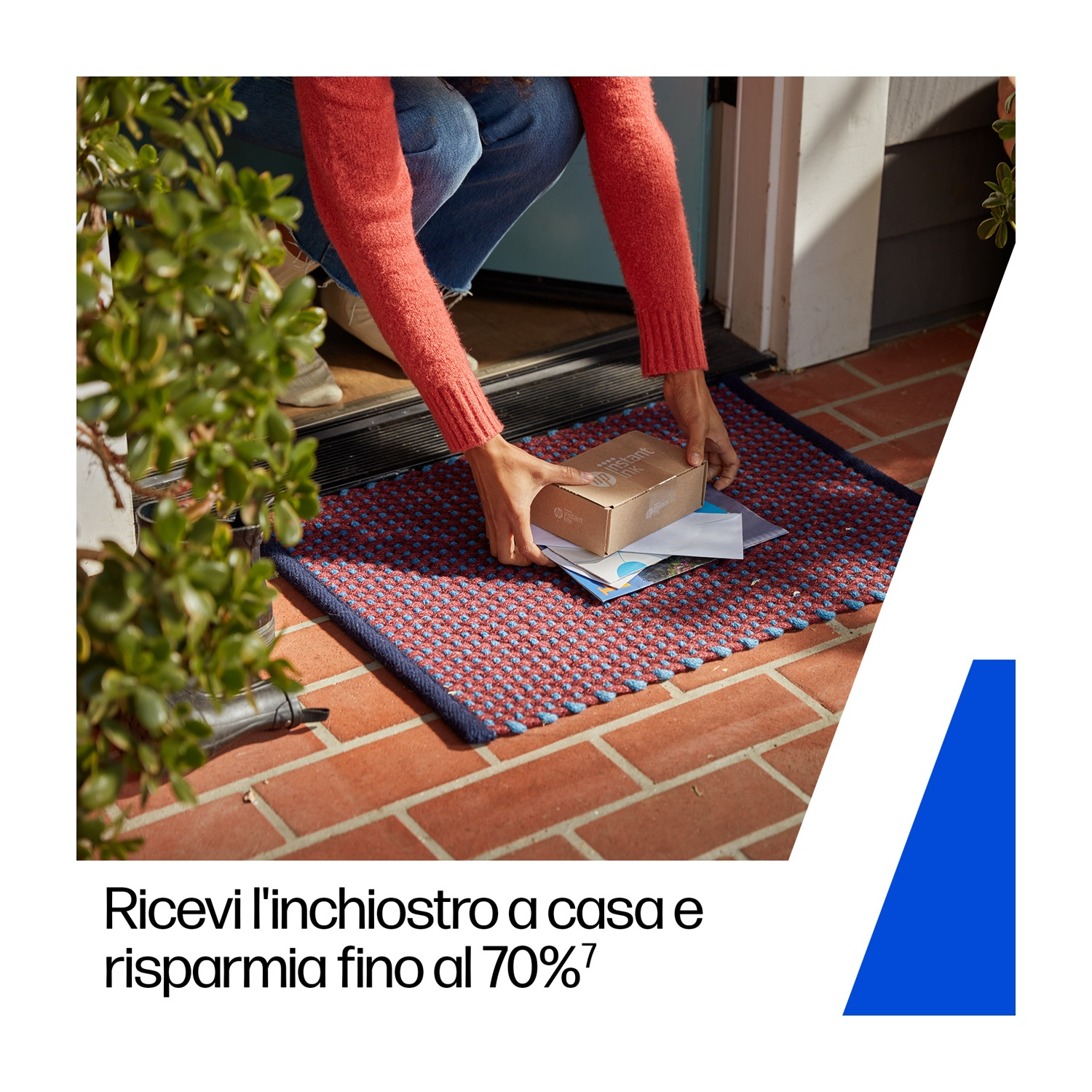 Persona che ritira un pacco da uno zerbino. Zerbino rosso e blu. Maglione rosso e jeans blu. Portico in mattoni e pianta verde.