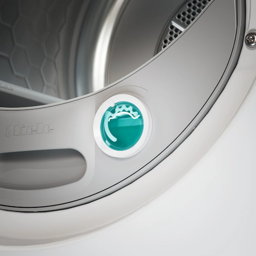 Nahaufnahme eines weißen Miele-Trockners. Ein türkisfarbenes Zifferblatt mit einem Wassertropfensymbol ist prominent.