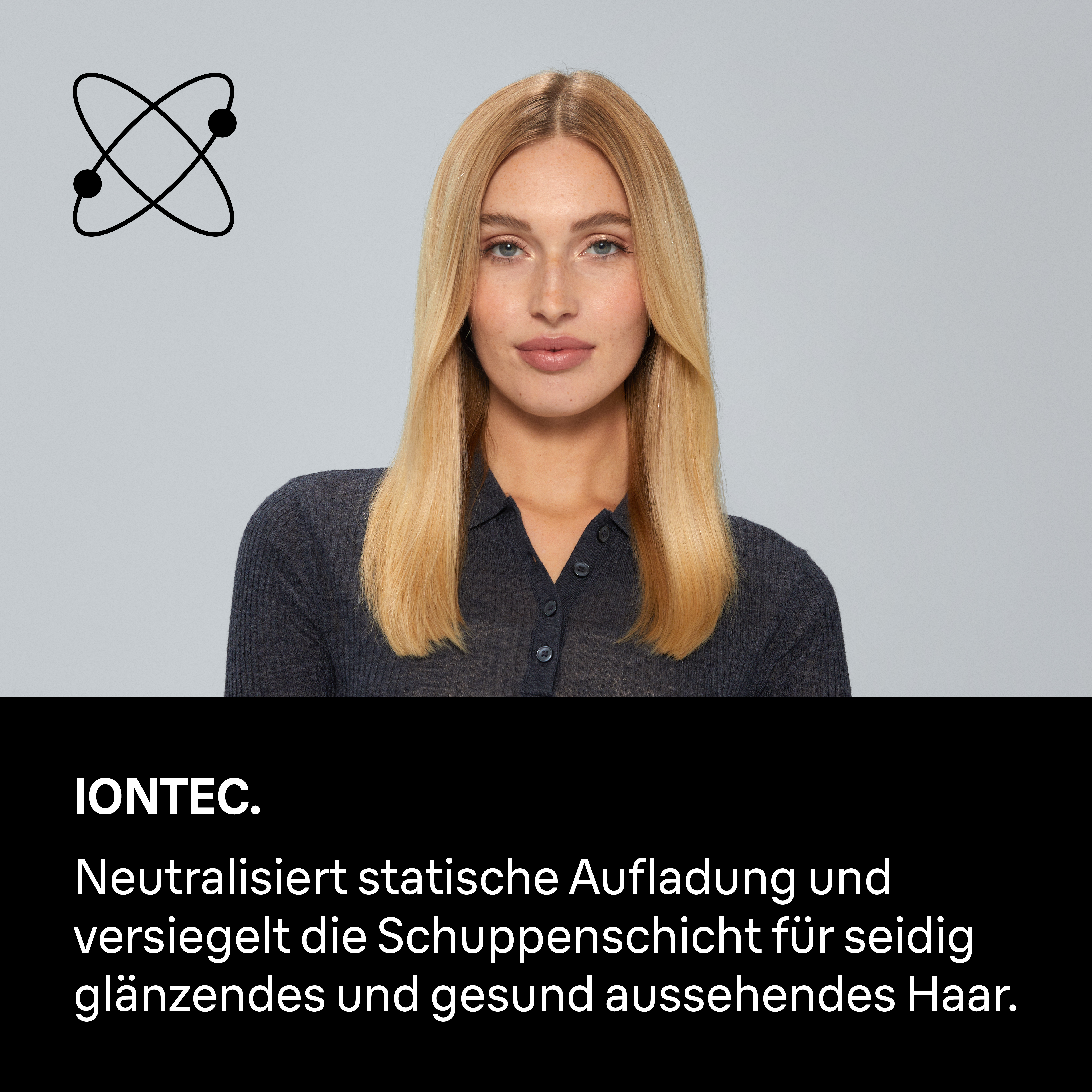 Eine Frau mit blonden Haaren, trägt ein dunkles Hemd. Ein Atomsymbol über ihrem Kopf.