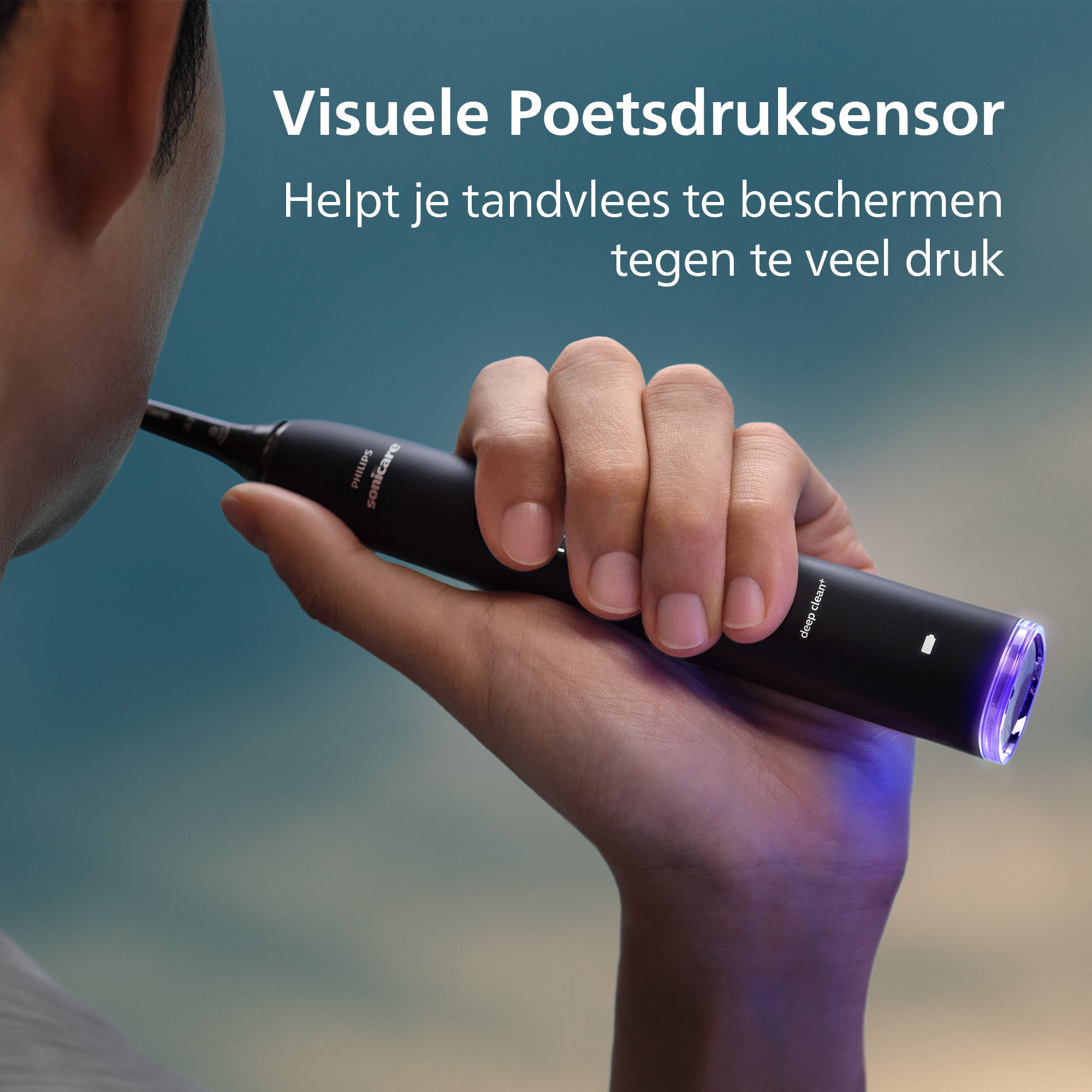 A person holds a black Philips Sonicare toothbrush. The brush lights up blue. Text reads: Visuele Poetsdruksensor.