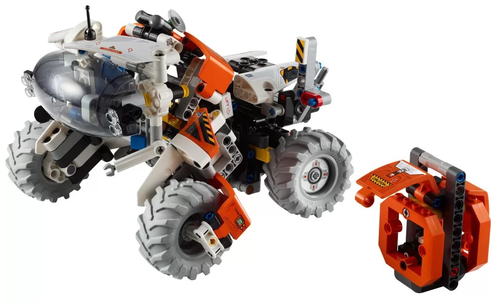 Lego Technic rover z dużymi szarymi kołami. Ma pomarańczowo-biały korpus z przezroczystą kopułą z przodu. Po prawej stronie znajduje się osobne pomarańczowe pudełko.