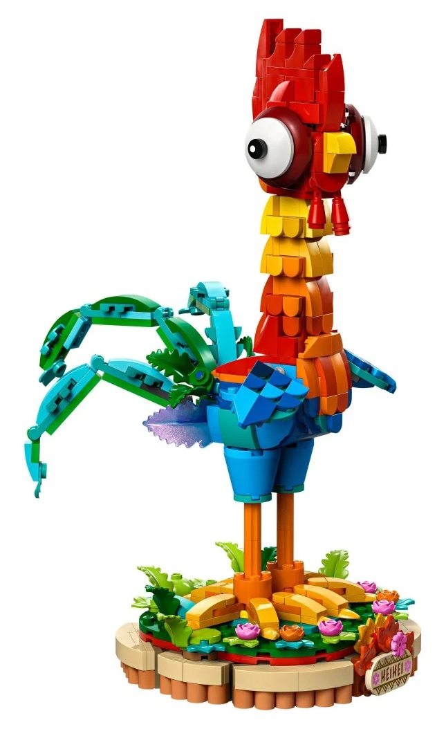 Model koguta Hei Hei z klocków Lego. Ma czerwone, żółte, pomarańczowe i niebieskie elementy. Stoi na podstawie z zieloną trawą i kwiatami.