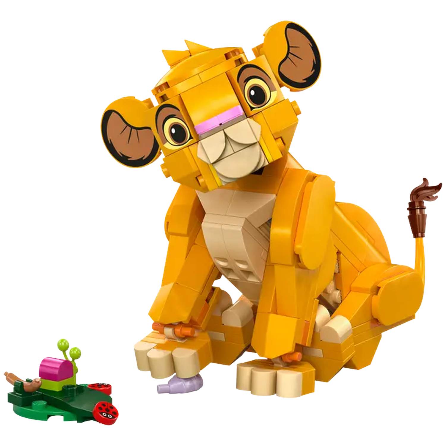 Un bébé Simba Lego est assis. Il est jaune avec des oreilles marron. Un petit objet Lego vert est à gauche avec des détails roses et rouges.