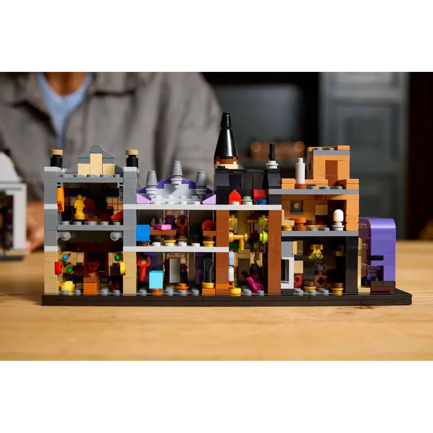 A Lego building with multiple rooms showcasing detailed interior design, various colors, and unique shapes. A person is slightly visible in the background.
