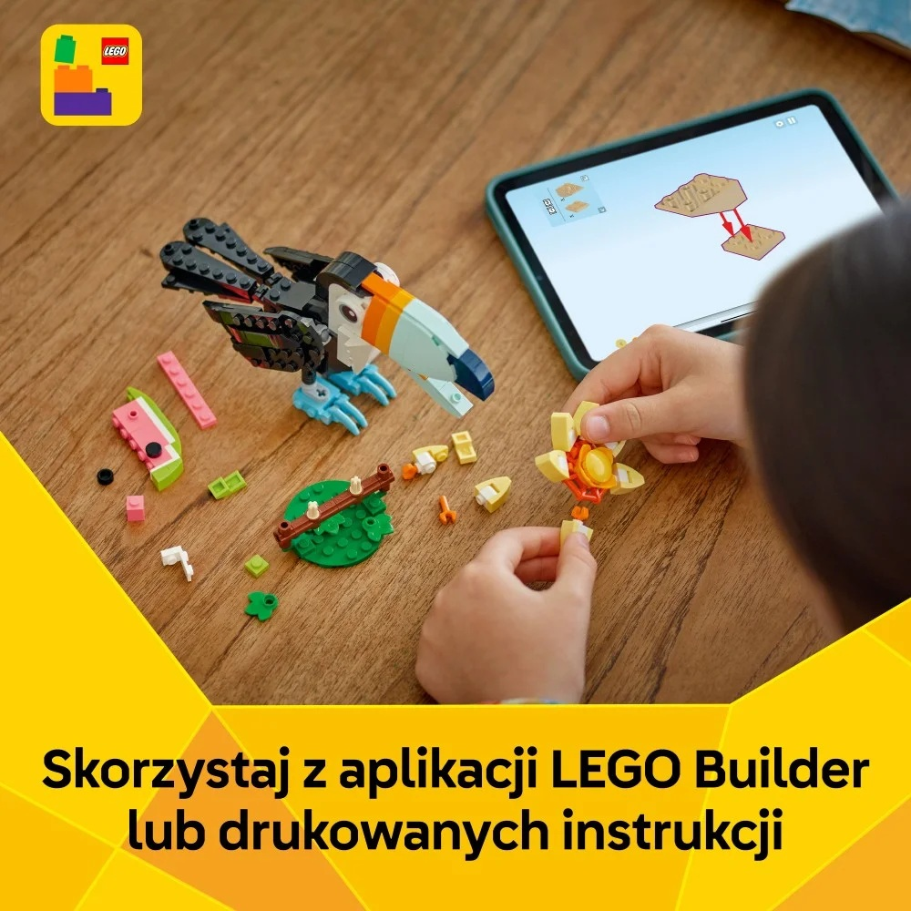 Dziecko składa model tukana LEGO. Ptak jest głównie czarno-biały, z pomarańczowym i niebieskim dziobem. Części są rozrzucone.