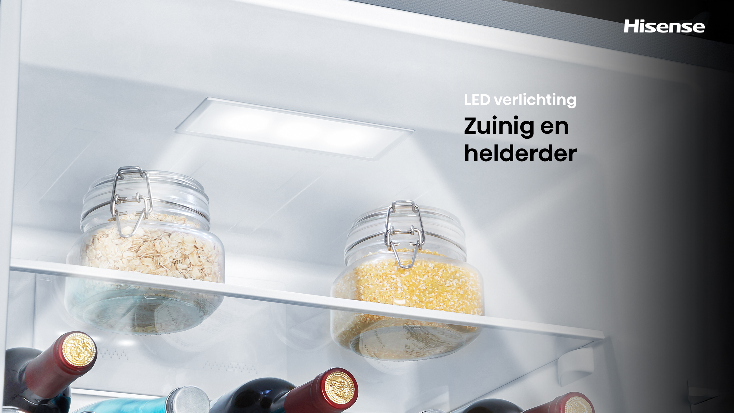 Inside a fridge, two jars with food. Wine bottles at the bottom, LED light at the top. Hisense logo in the corner.