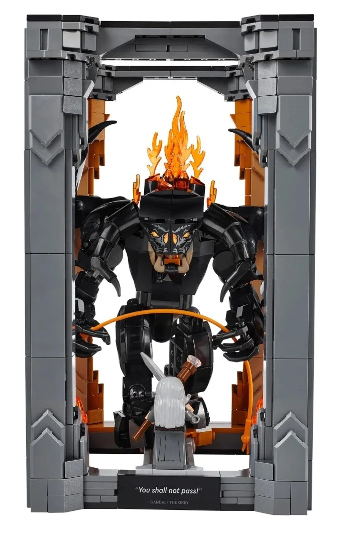 Scena Lego z Gandalfem kontra Balrogiem. Balrog jest czarny z ogniem na głowie. Gandalf staje naprzeciw niego z mieczem. Szara konstrukcja z cegieł.
