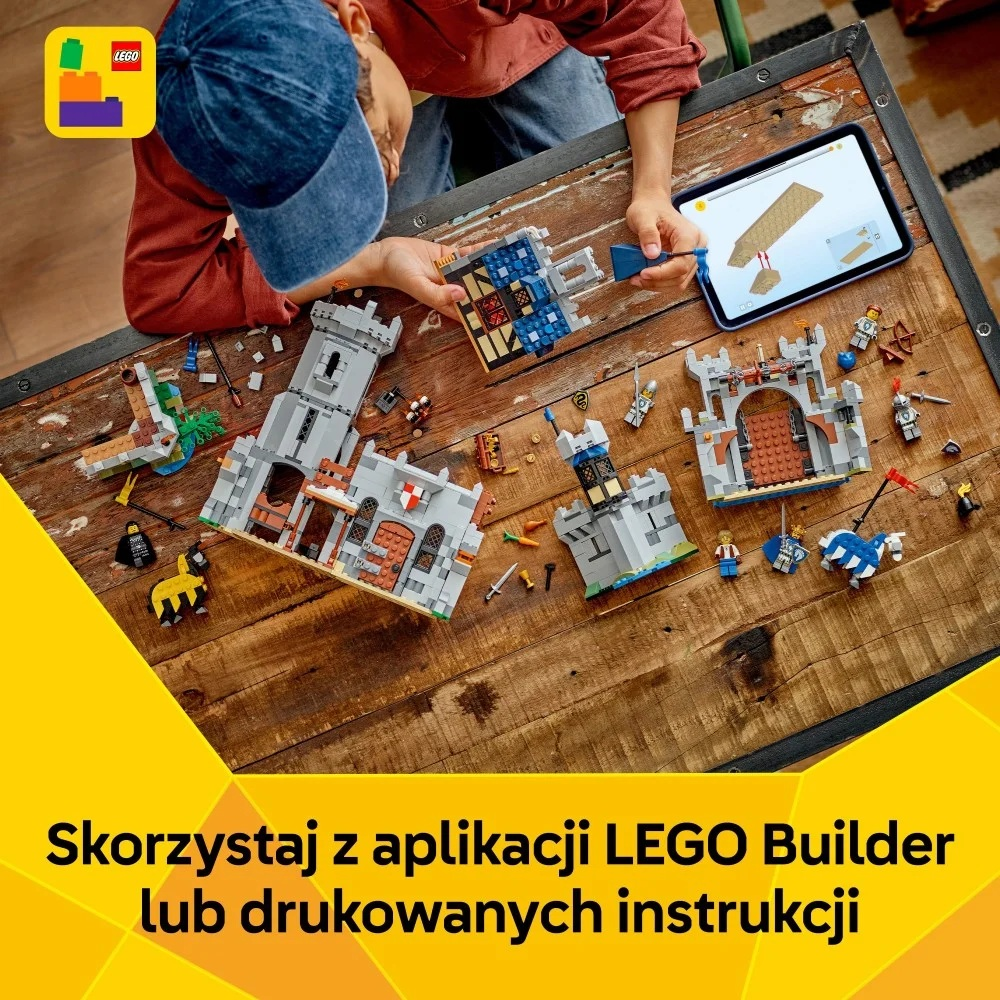 Dziecko buduje zamek Lego na drewnianym stole, używając tabletu. Klocki i figurki Lego są rozrzucone.