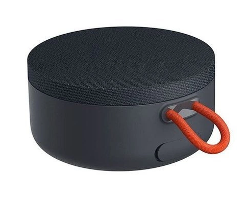 Ciemnoszary, okrągły głośnik przenośny z czarnym siatkowym wierzchem i pomarańczowym uchwytem pętelkowym.