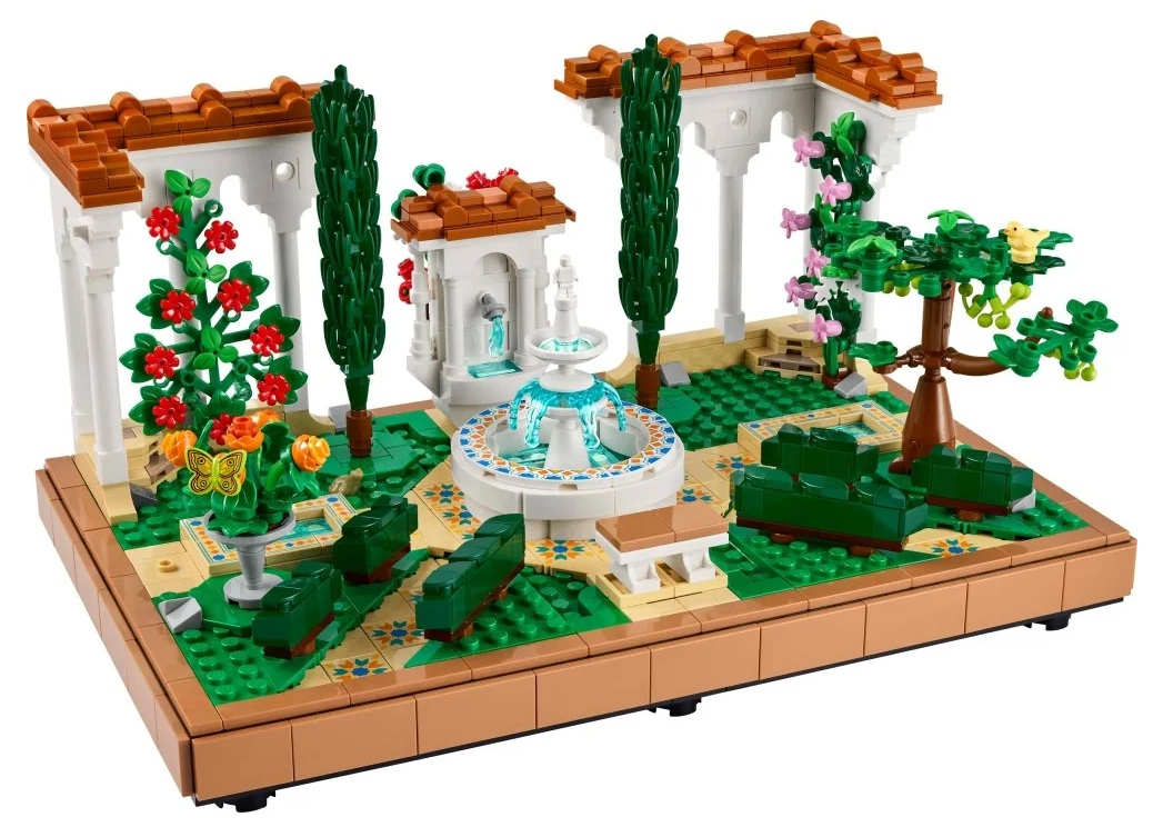 Model Lego ogrodu z fontanną, drzewami, kwiatami i małym budynkiem z łukami i dachem z płytek.