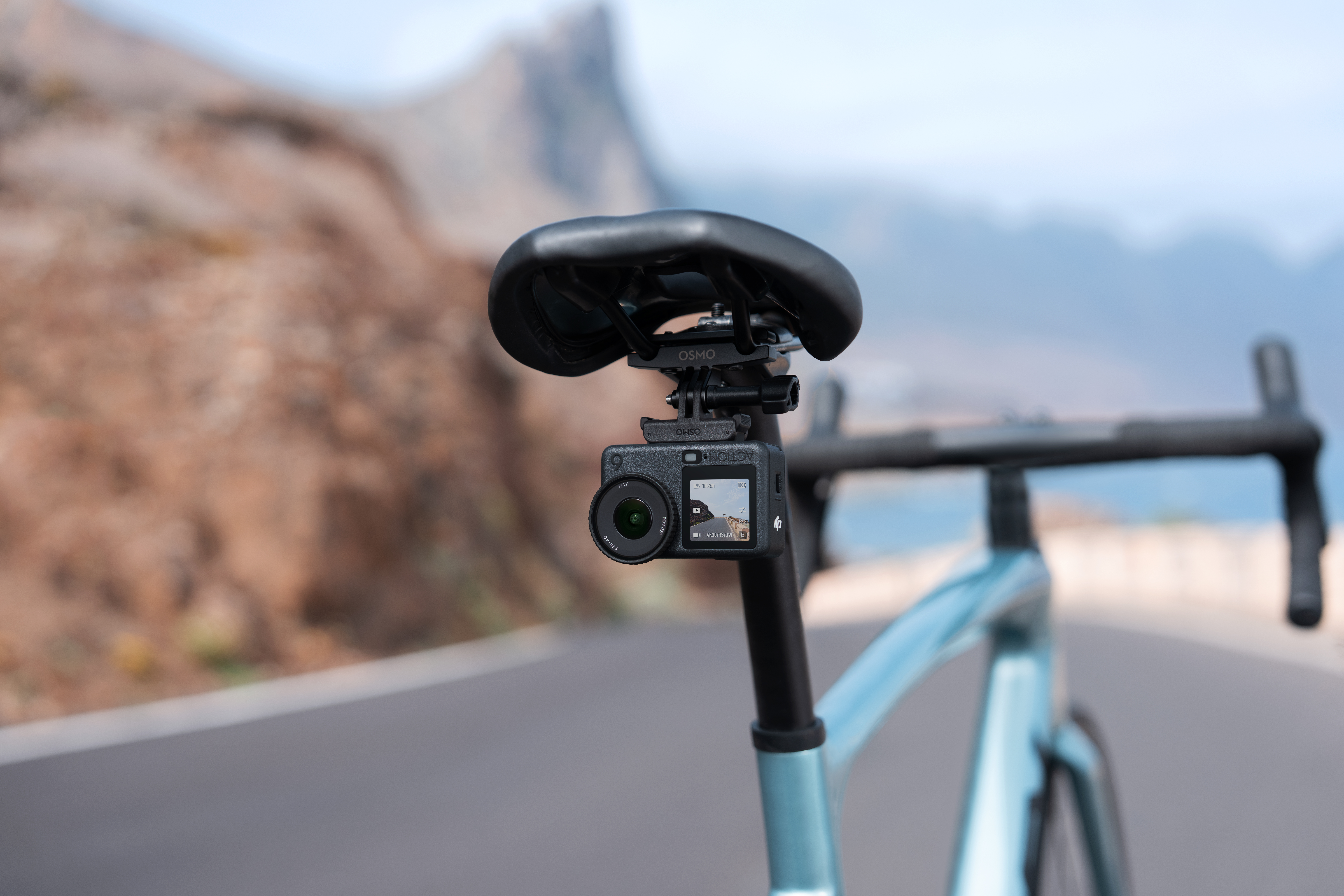 Siodło rowerowe z kamerą. Kamera pokazuje scenę drogową. W tle góry.