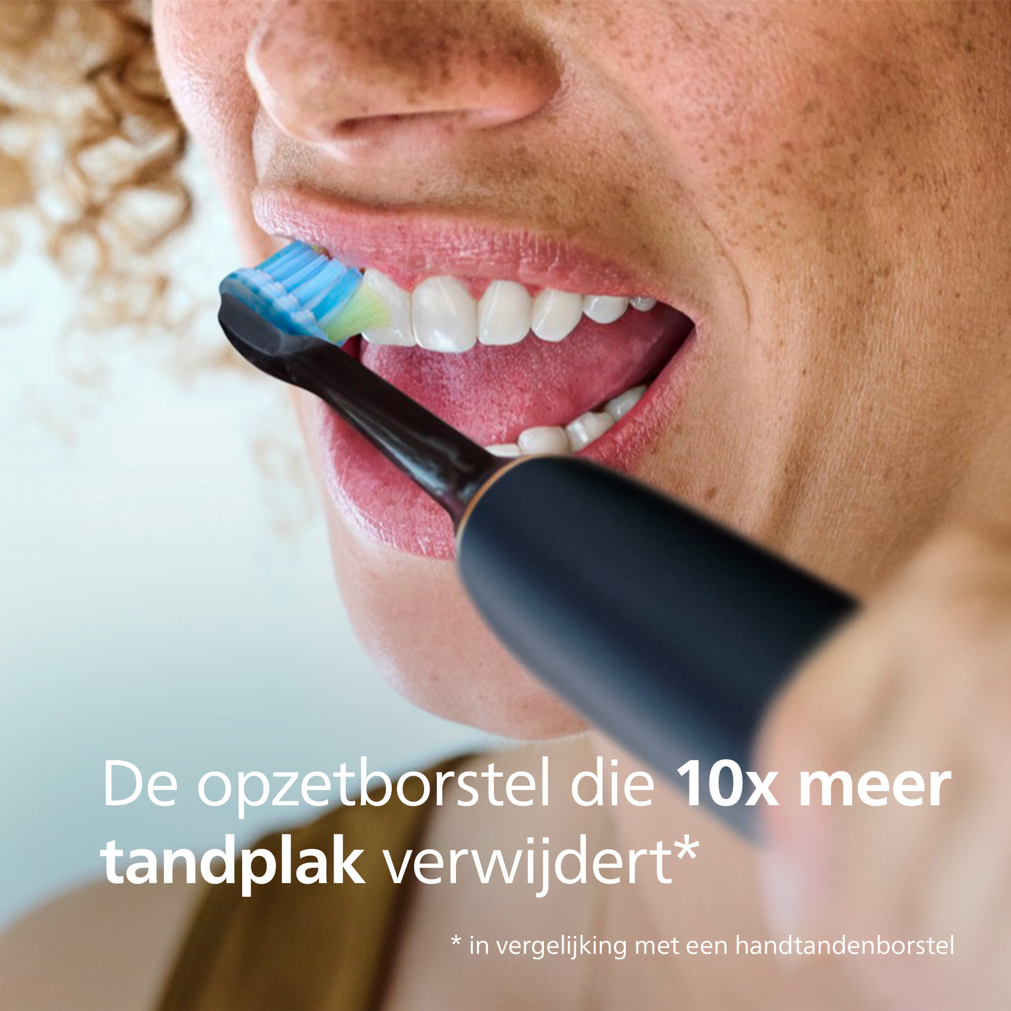 Close-up of a person brushing teeth with a black electric toothbrush. The brush head is blue and green.