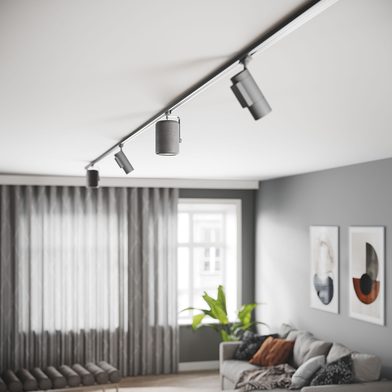 Een moderne woonkamer met railverlichting aan het plafond. Een grijze bank, kunst en gordijnen zijn zichtbaar.