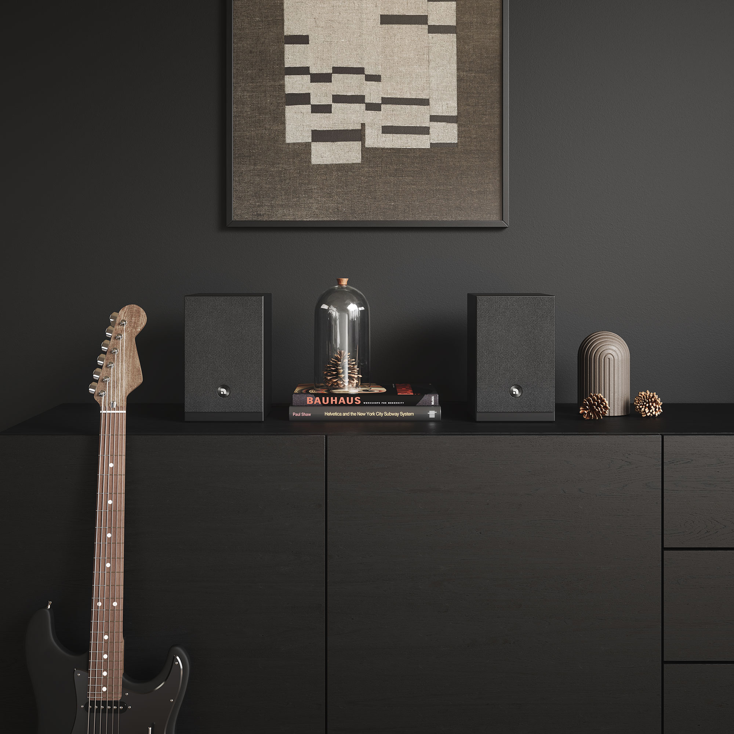 Een zwarte gitaar leunt tegen een zwarte kast. Twee speakers, een glazen koepel en kunst staan erop. Donkere muur.