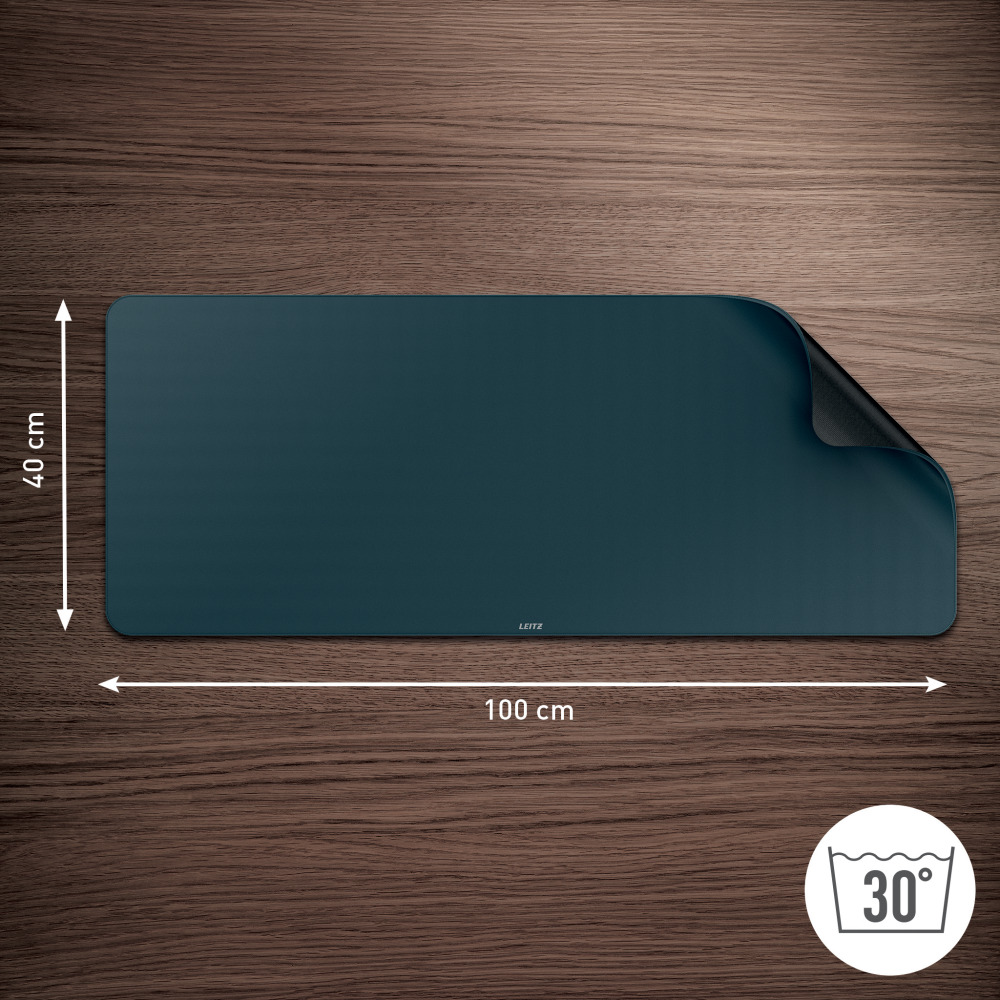 Egy sötétkék téglalap alakú szőnyeg a fa felületen. A szőnyeg 100x40cm. A sarok hajtott, fekete oldala látható.