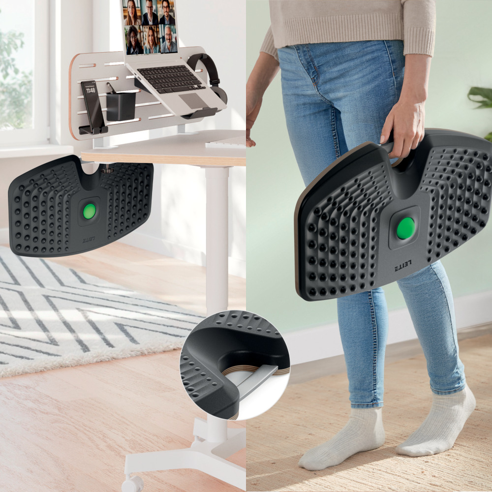 Egy személy egy fekete lábtartót tart zöld gombbal. A háttérben egy laptopot, telefont és headsetet tartalmazó íróasztal.