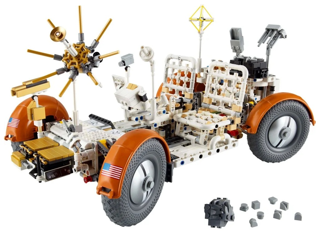 Model Lego łazika księżycowego, biało-pomarańczowy z szarymi kołami. Posiada anteny, siedzenia i różne szczegółowe elementy.