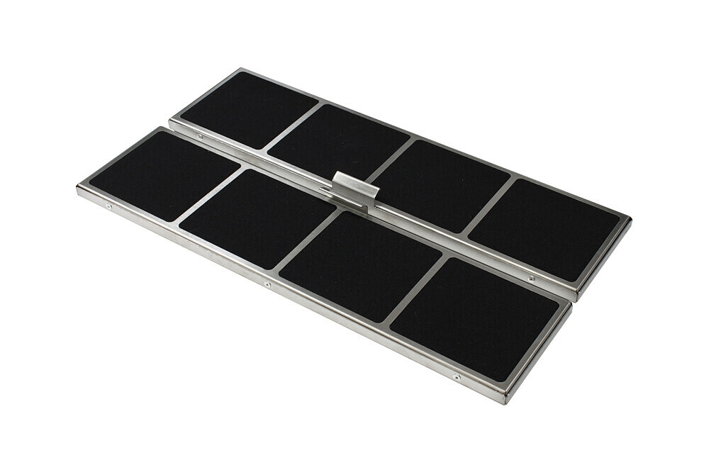 Ein Metallobjekt mit schwarzen, quadratischen Pads. Es ist in der Mitte angelenkt und liegt auf einer weißen Oberfläche.