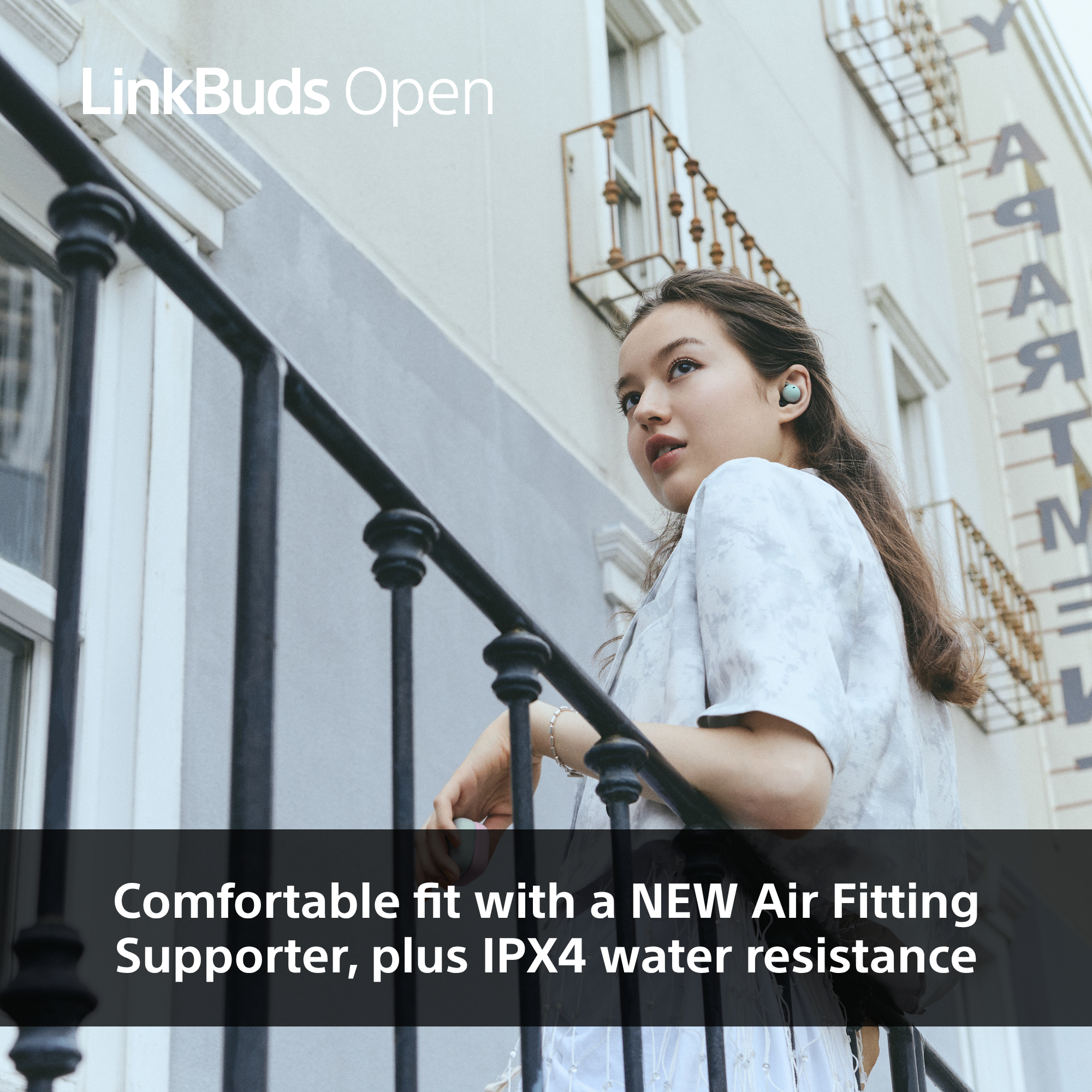 Femme portant des écouteurs sur un balcon. Texte : Ajustement confortable avec un NOUVEAU Air Fitting Supporter, plus résistance à l'eau IPX4.