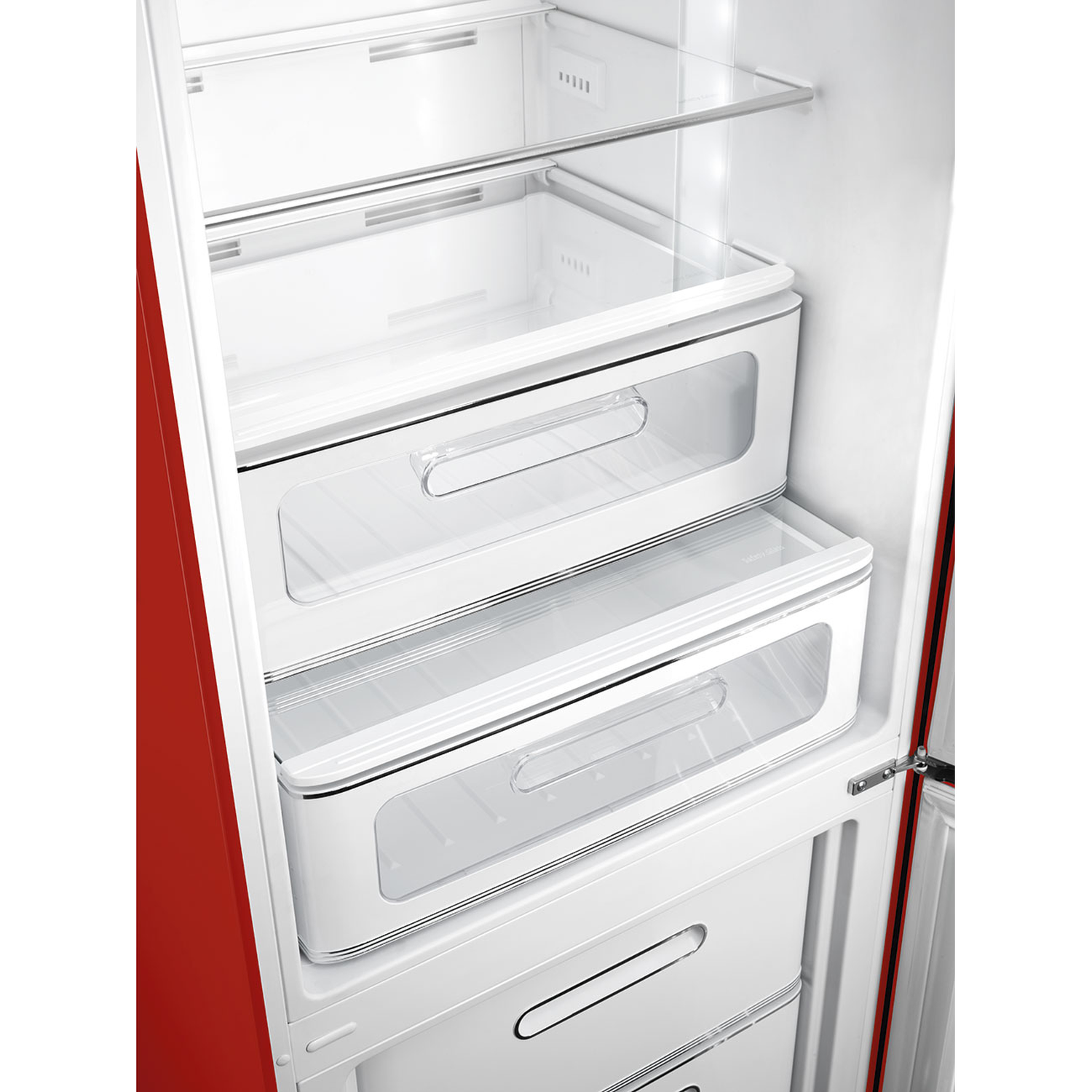 Open refrigerator interior. White shelves and drawers inside a red and white fridge. Clear plastic drawer fronts and handles.