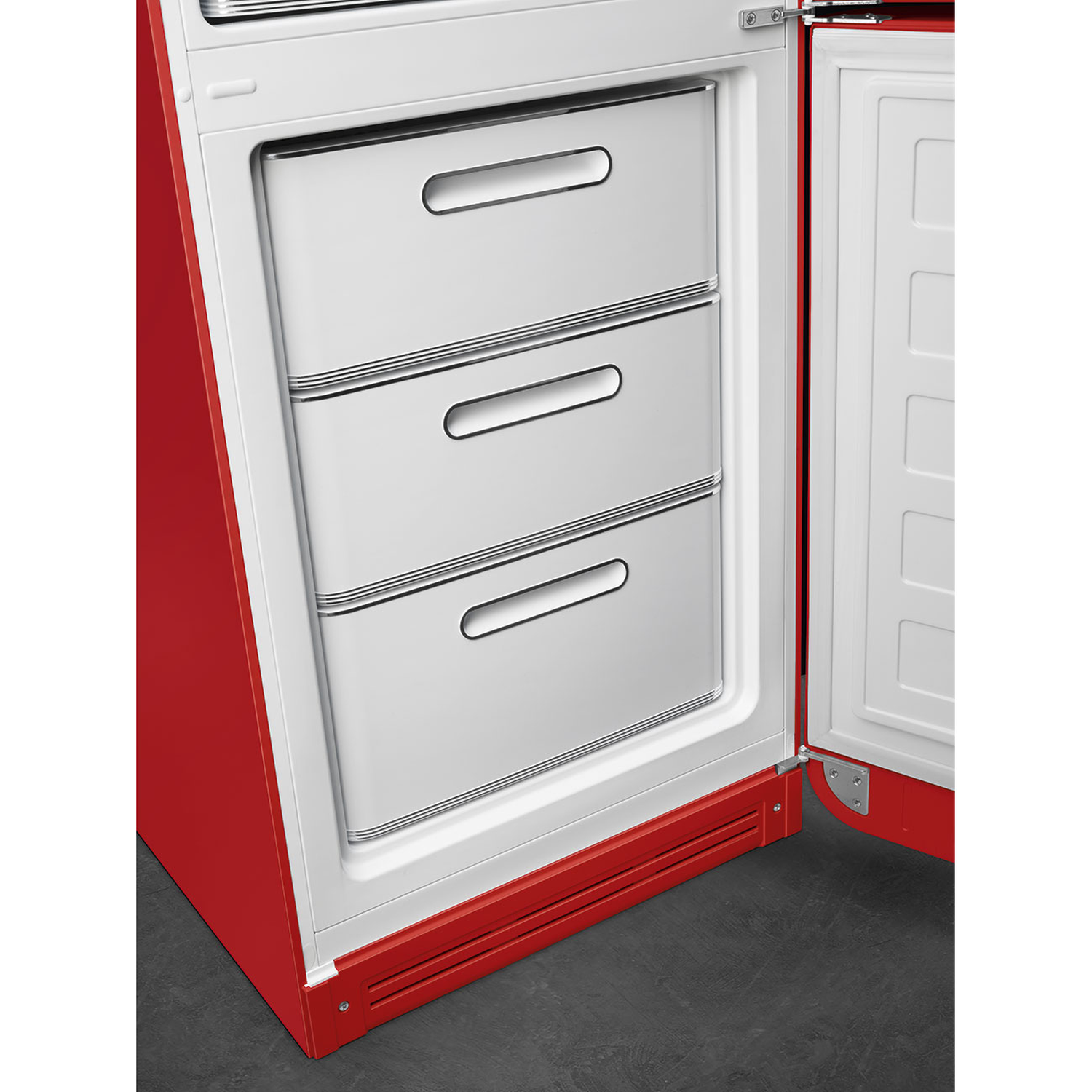 Open red refrigerator with three drawers and open door. White interior, grey floor.