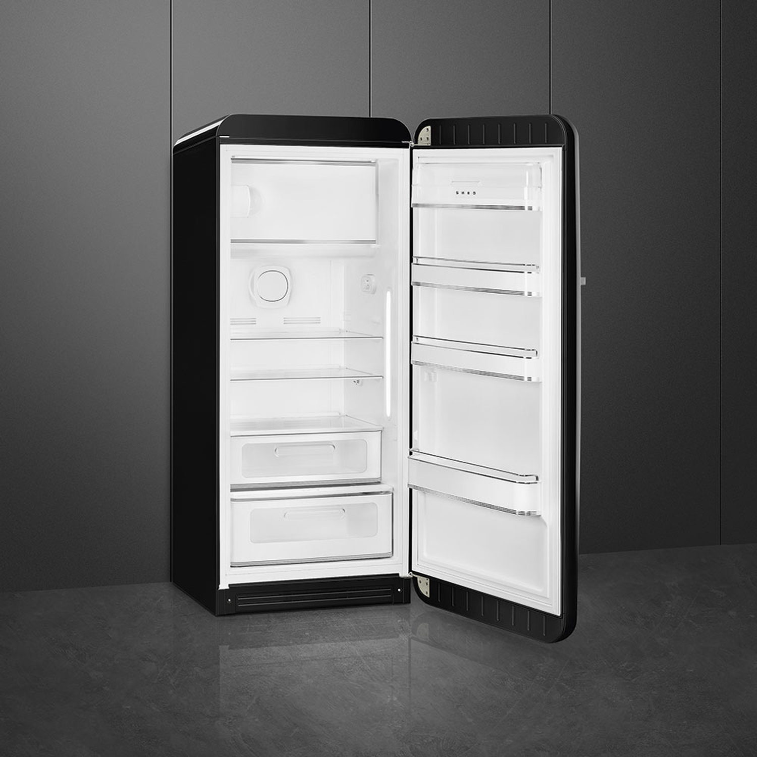 A black Smeg refrigerator with its door open. The interior is white with shelves and drawers. It's against a dark gray wall.