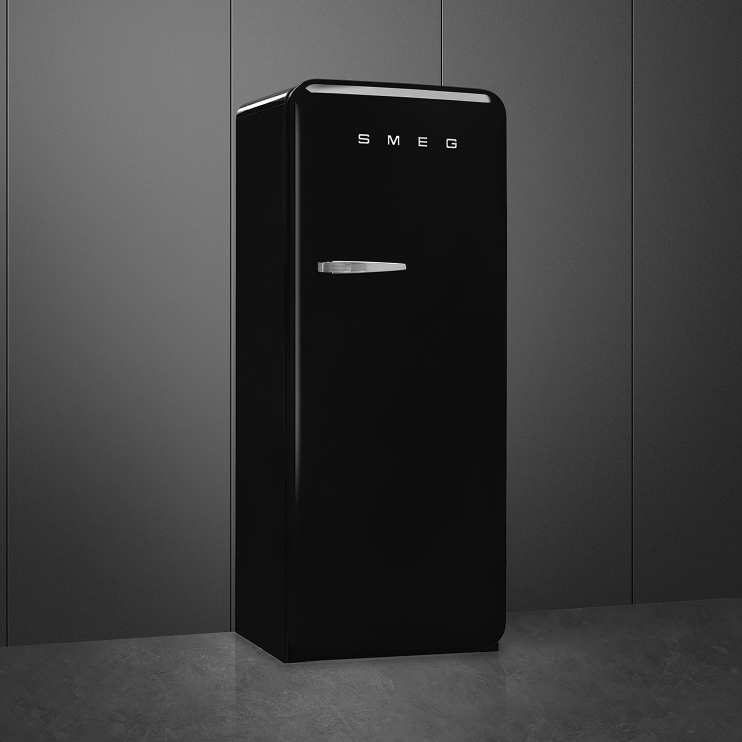 A black SMEG refrigerator stands against a dark gray wall. It has a silver handle and the SMEG logo at the top.