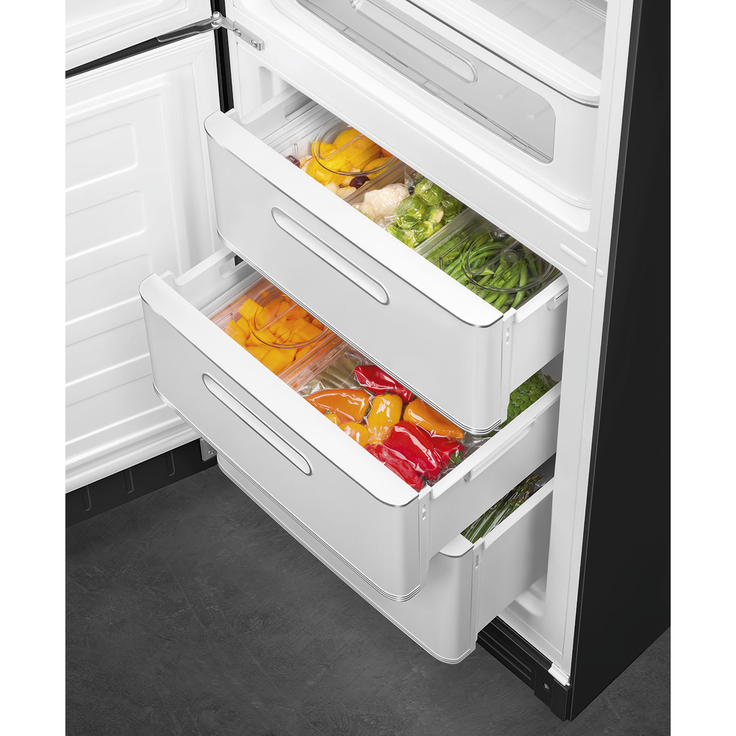 Open koelkast met laden vol kleurrijke paprika's, sperziebonen en andere groenten. Zwart-wit interieur.