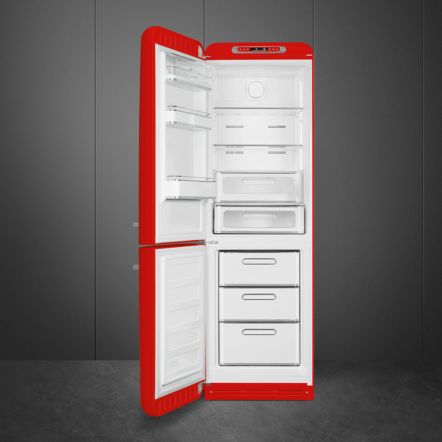 Open red refrigerator with white interior. Shelves, drawers are visible. Background is gray wall and floor.