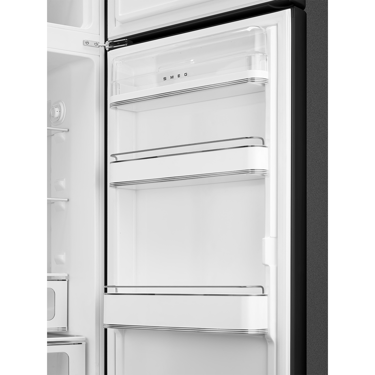 Open koelkastinterieur met witte planken en een doorzichtige bovenste plank. De deur is open, met zwarte buitenkant en SMEG-logo.