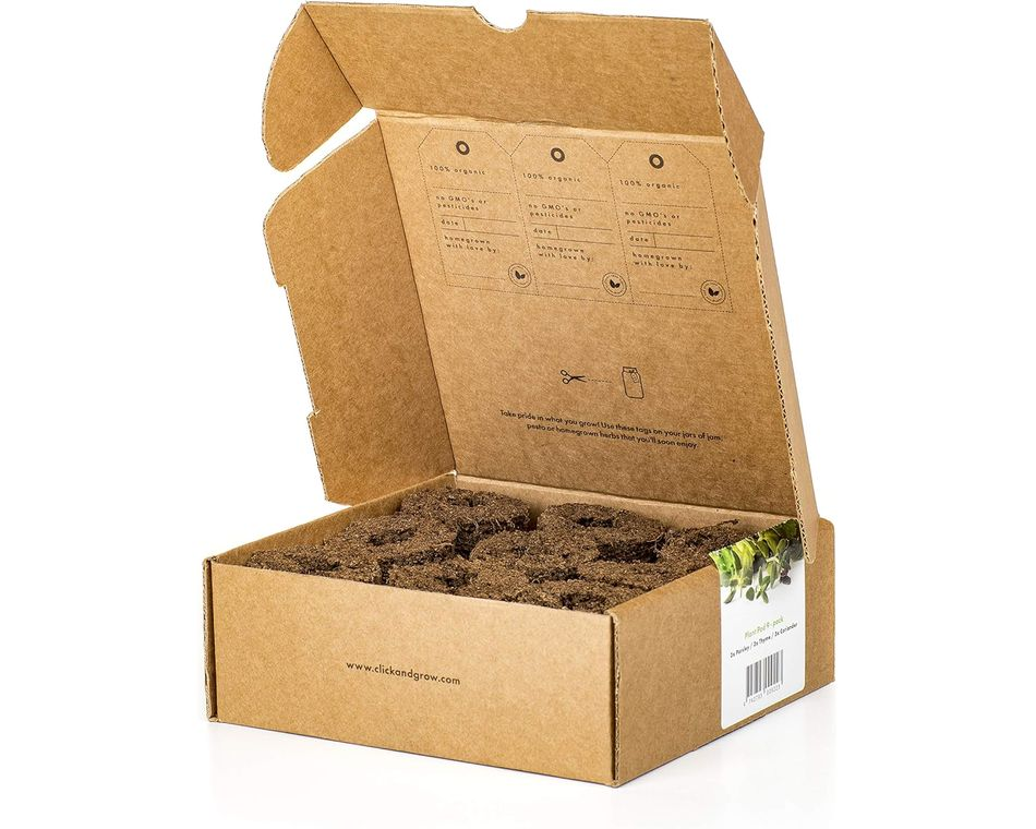 Nyitott kartondoboz földhüvelyekkel. A dobozon nyomtatott címkék és egy termékcímke található. A www.clickandgrow.com weboldal látható.