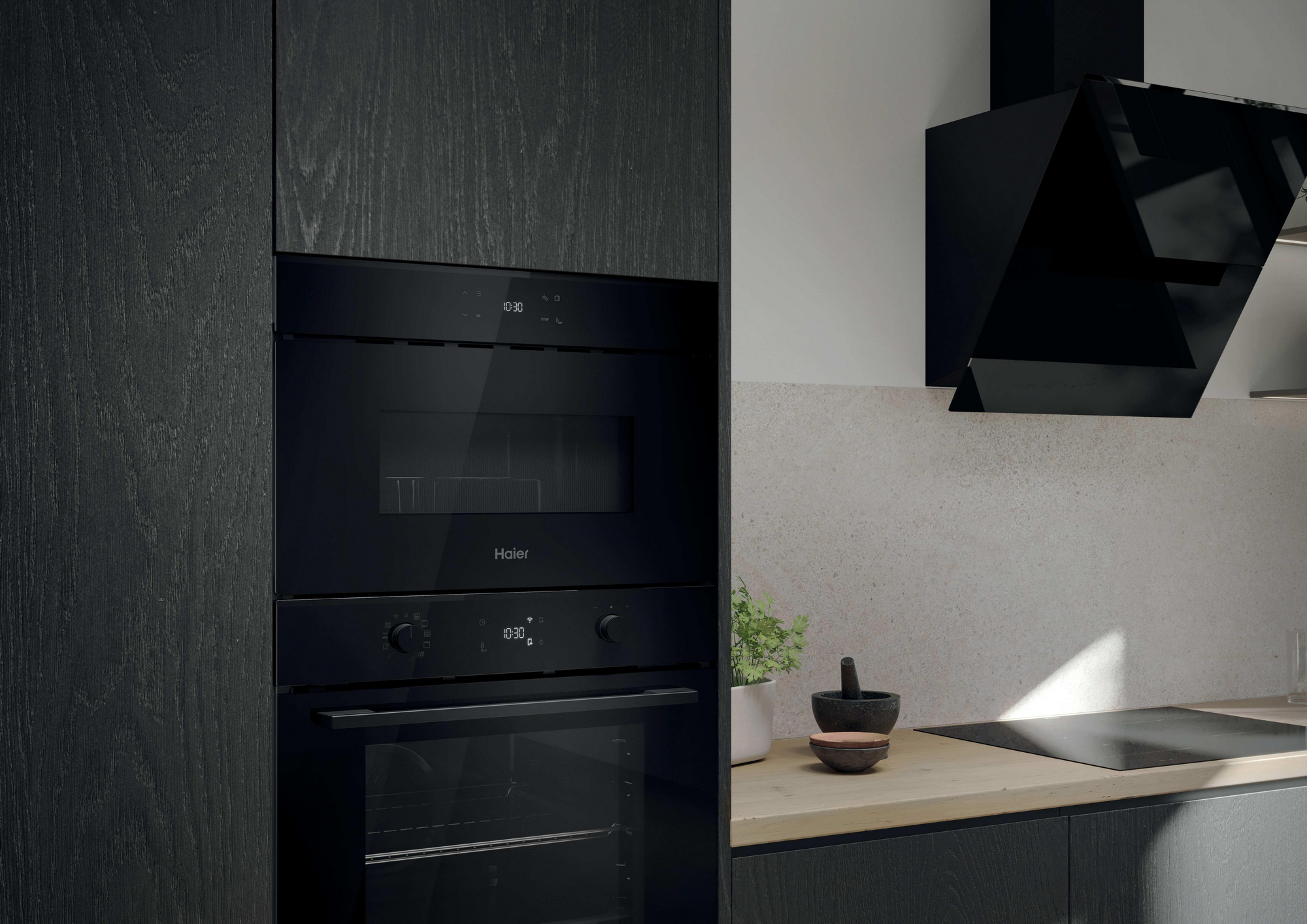 Una cocina moderna con electrodomésticos negros, incluyendo un horno y una campana extractora. Una planta, mortero y cuencos sobre la encimera de madera.