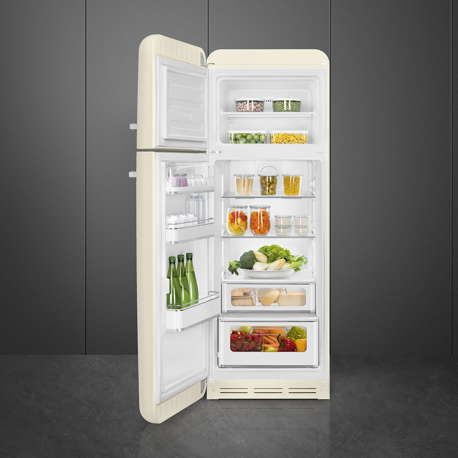 Open cream-colored refrigerator filled with food: vegetables, fruits, jars. Grey background.