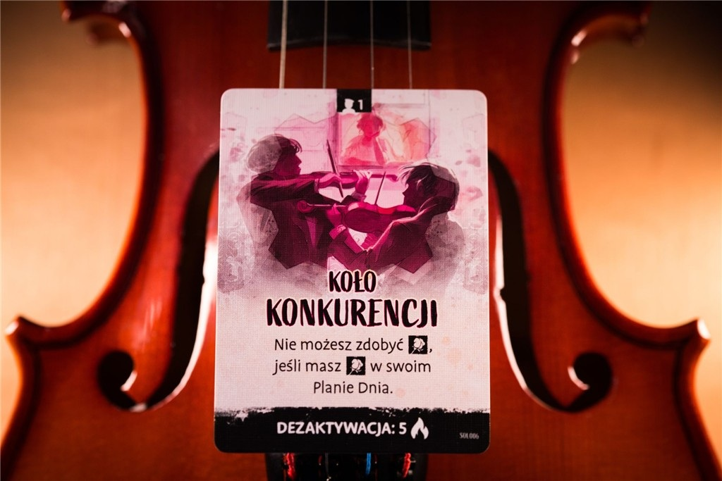 Karta z obrazem skrzypiec. Dwie postacie grają na skrzypcach. Tekst polski: Konkurencja. Tekst na karcie przed skrzypcami.