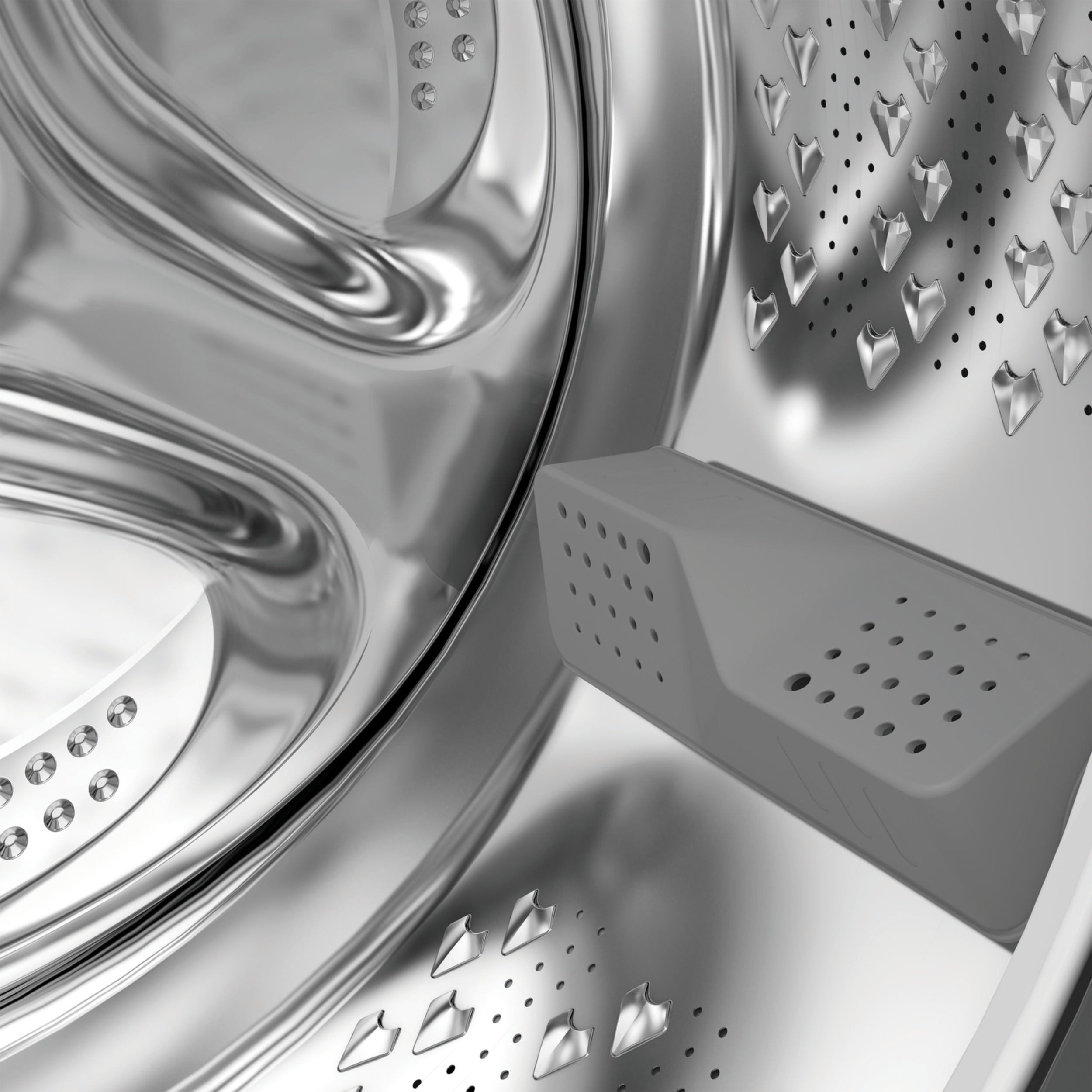 Wnętrze bębna pralki. Srebrne, metalowe powierzchnie i szary plastikowy element z otworami.