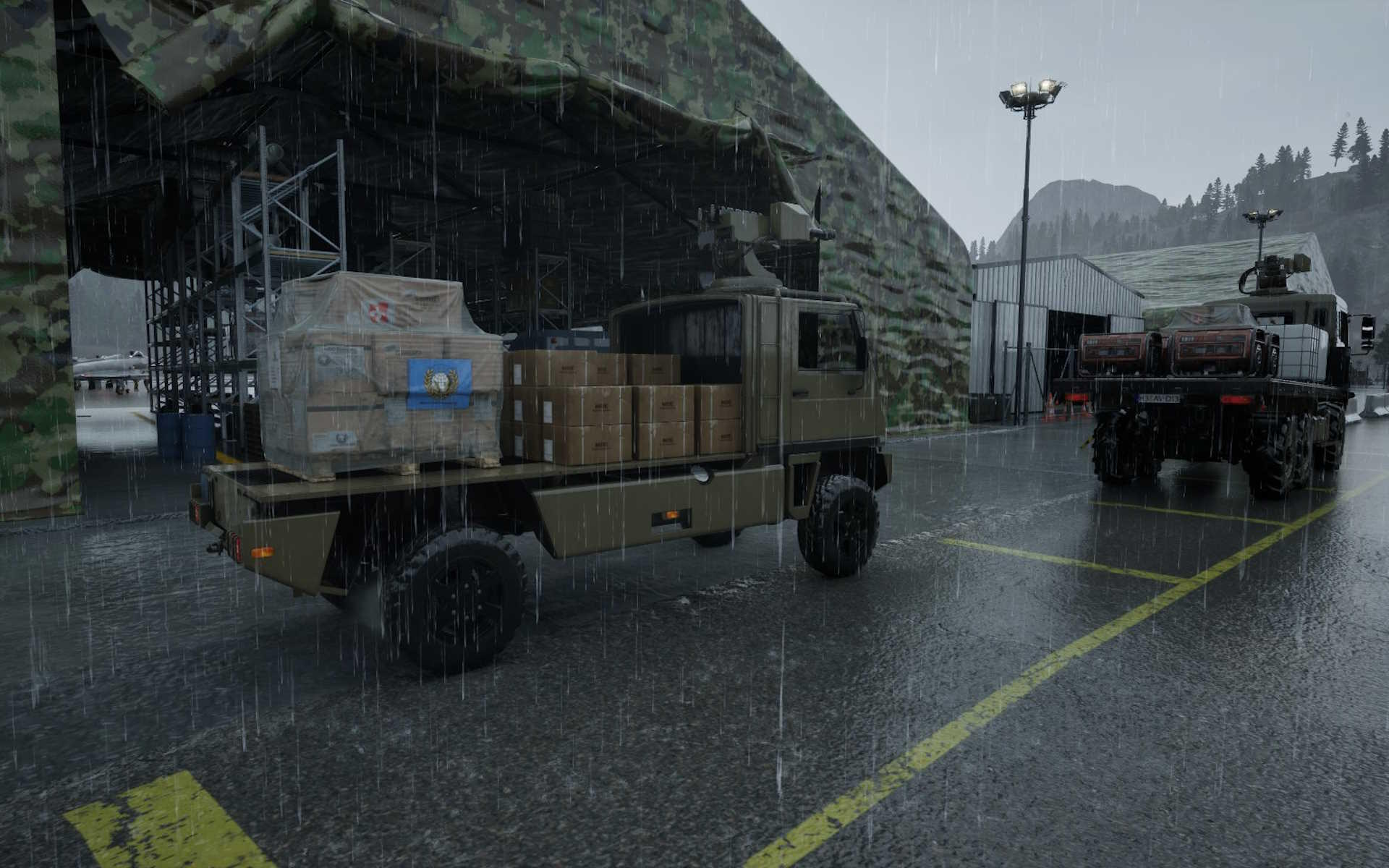 Zwei Militär-Lkw im Regen, einer mit Kisten beladen. Im Hintergrund ein Hangar und Berge. Es regnet.