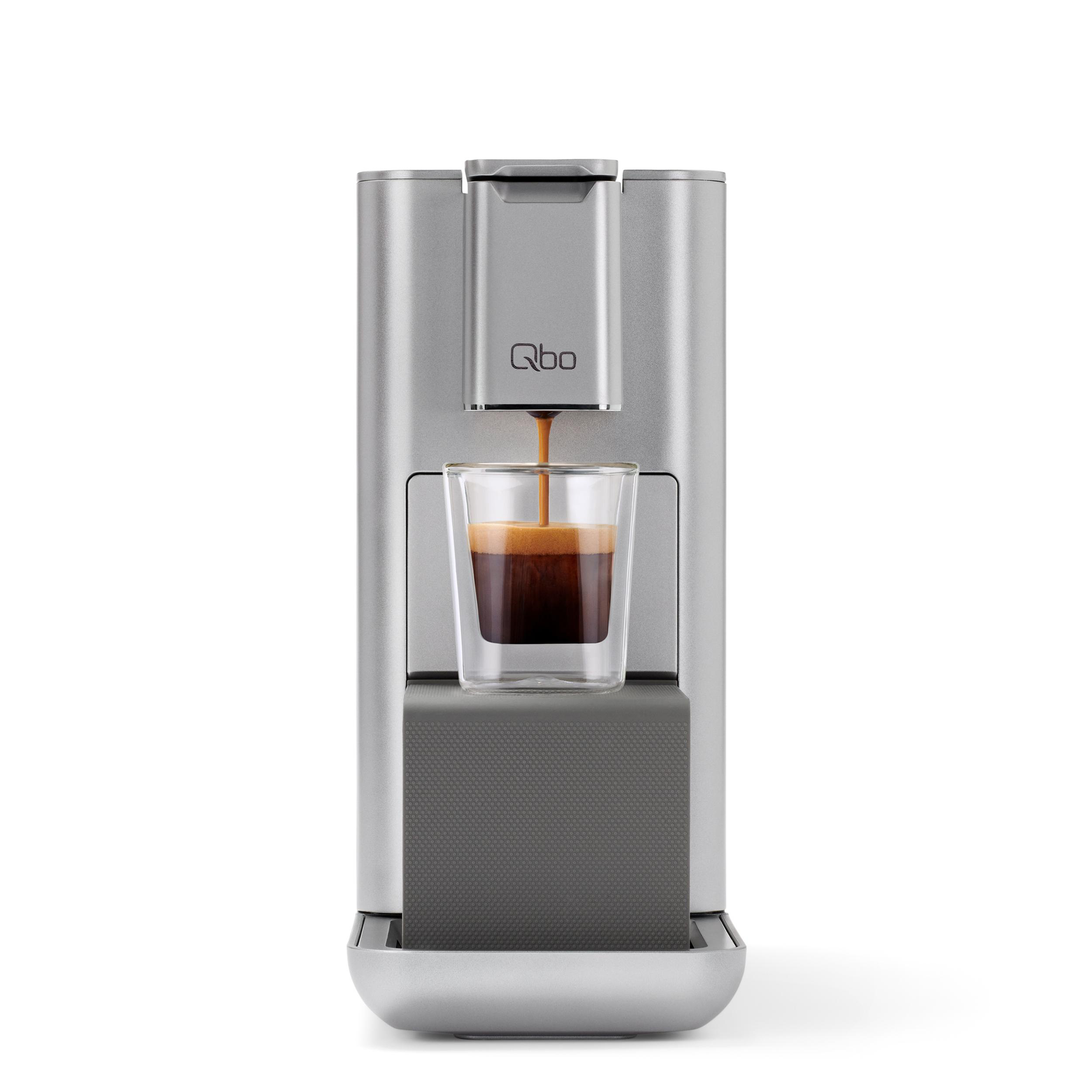 Silberne Kaffeemaschine, die Espresso in eine Glastasse ausgibt. Die Maschine hat das Logo 'Qbo'.