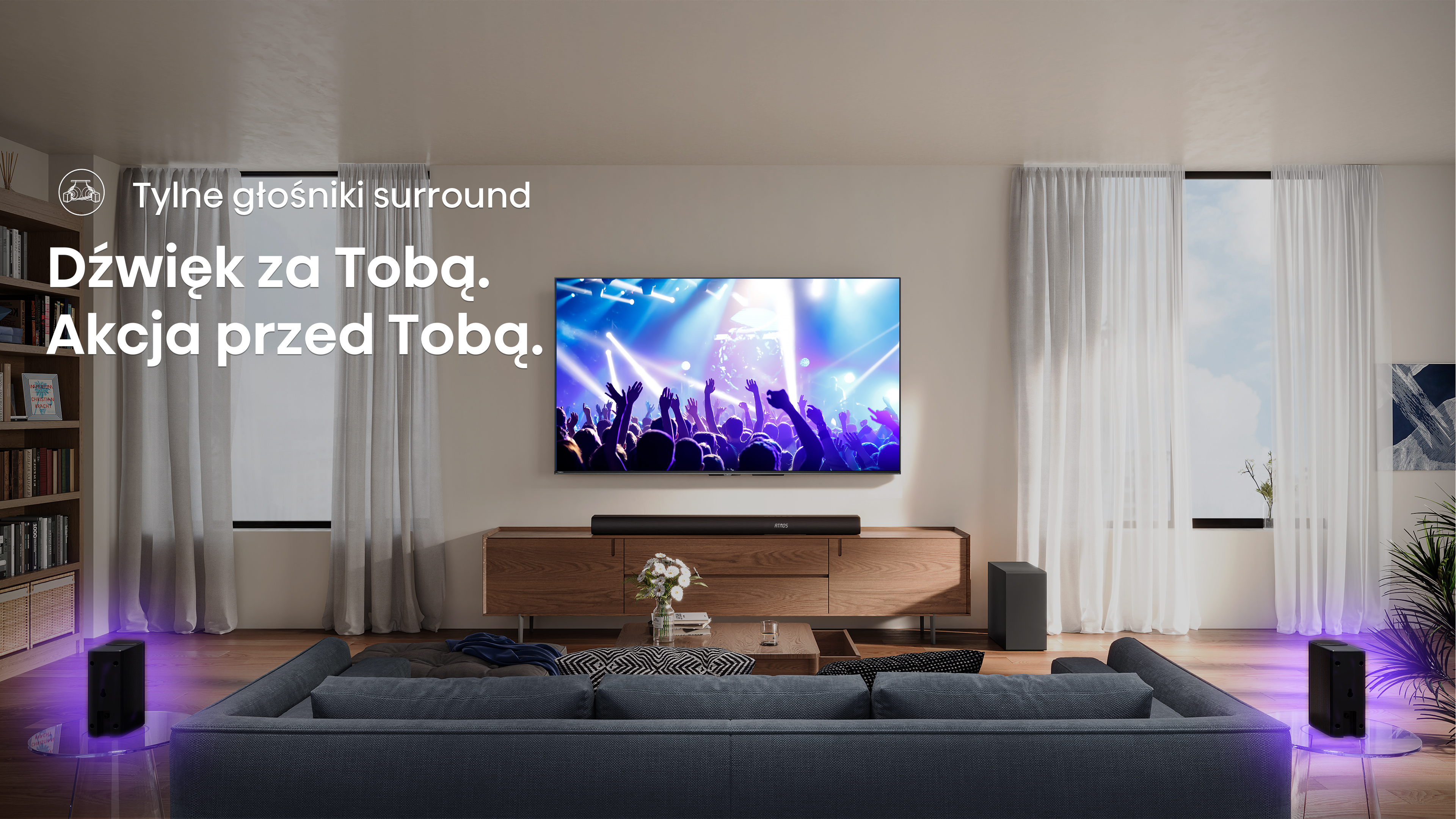 Salon z telewizorem z koncertem, głośnikami, sofą i soundbarem. W tle zasłony i okna.