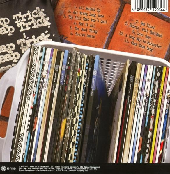 Eine Sammlung von Cheap Trick-Alben in einem weißen Korb. Ein schwarzes T-Shirt und ein orangefarbener Hintergrund mit Songtiteln sind sichtbar.