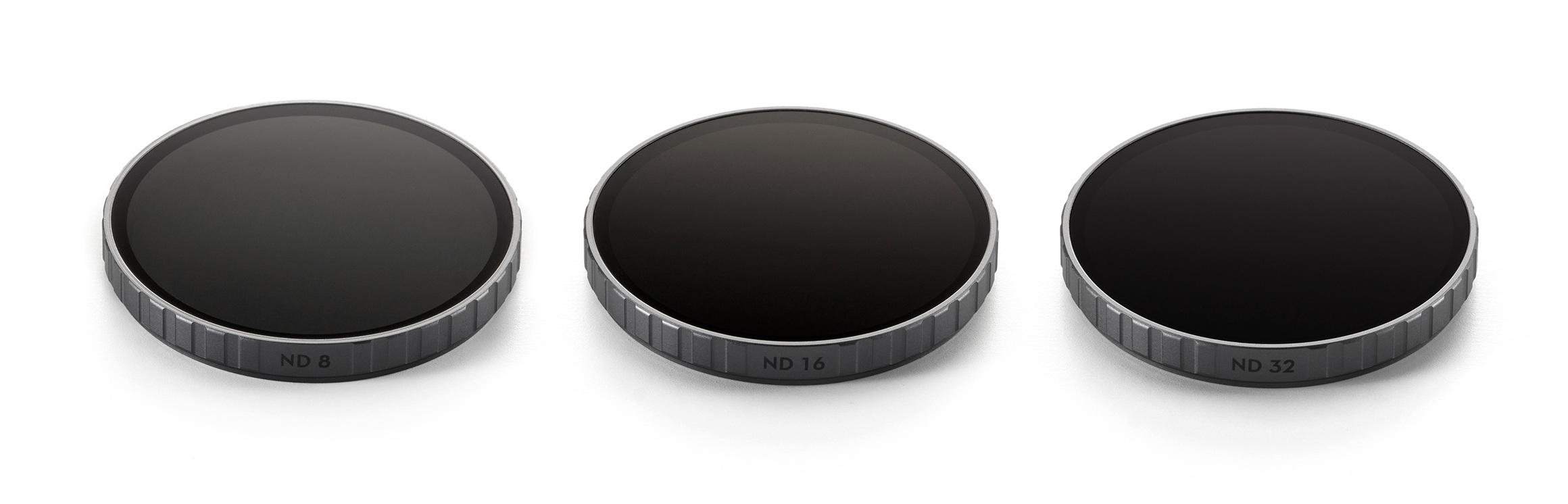 Trzy okrągłe filtry do aparatu z oznaczeniami ND 8, ND 16 i ND 32. Czarne z szarymi metalowymi obwódkami, na białym tle.
