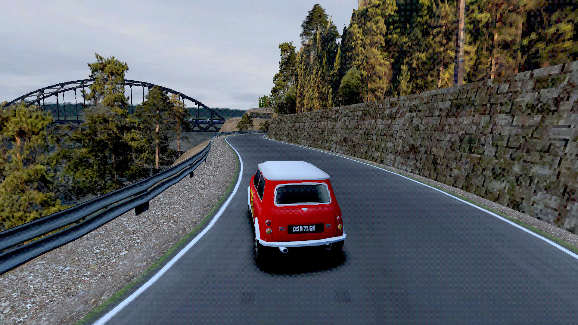 Roter und weißer Mini Cooper fährt auf einer kurvenreichen Straße. Bäume und eine Steinmauer säumen die Straße. Im Hintergrund ist eine Brücke zu sehen.