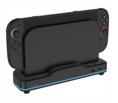 Czarna stacja dokująca Nintendo Switch z dołączonymi kontrolerami. Niebieskie i czerwone akcenty. Widoczny port USB.