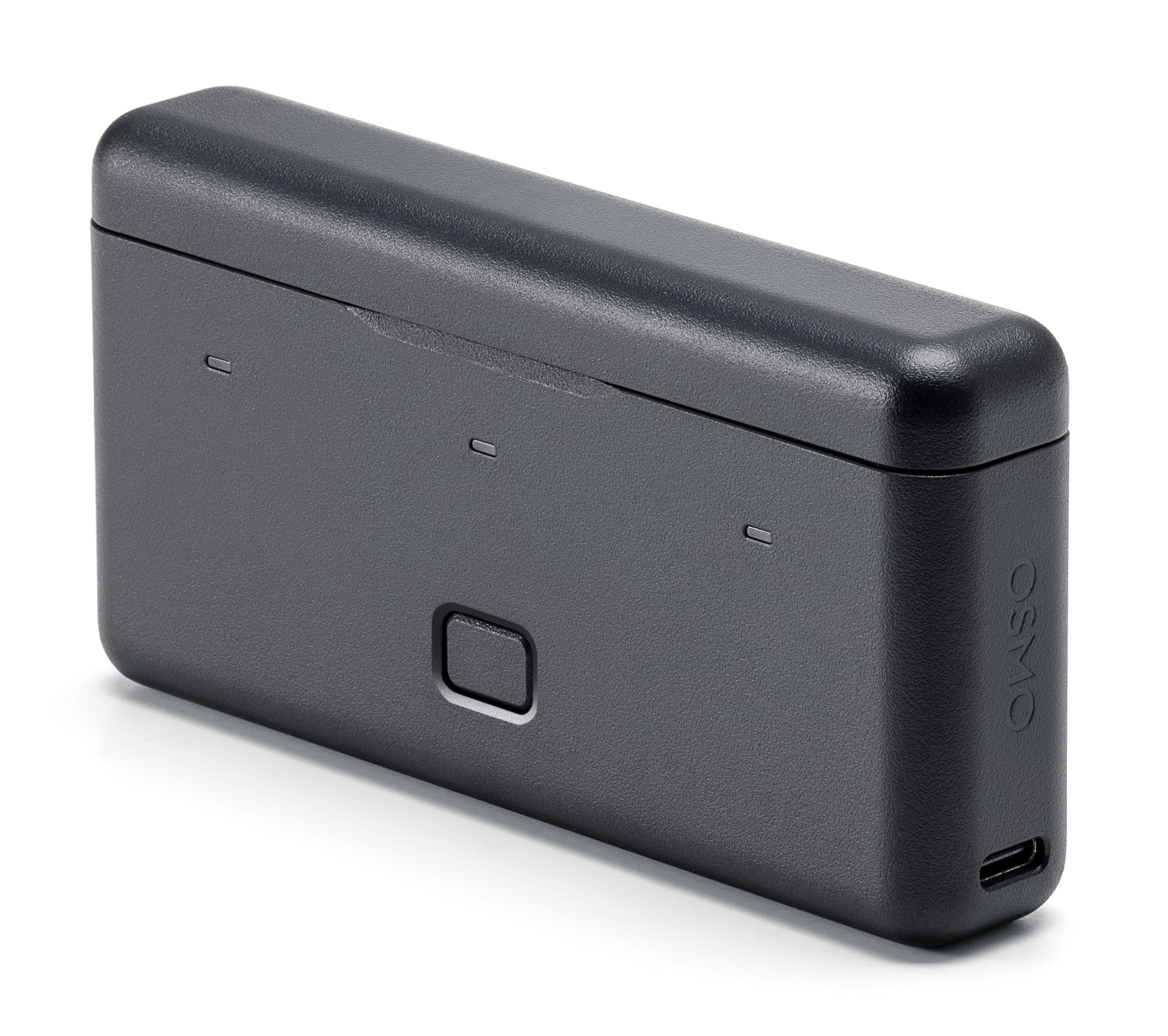 Czarne prostokątne urządzenie z zaokrąglonymi krawędziami. Posiada przycisk zasilania i kilka małych otworów.